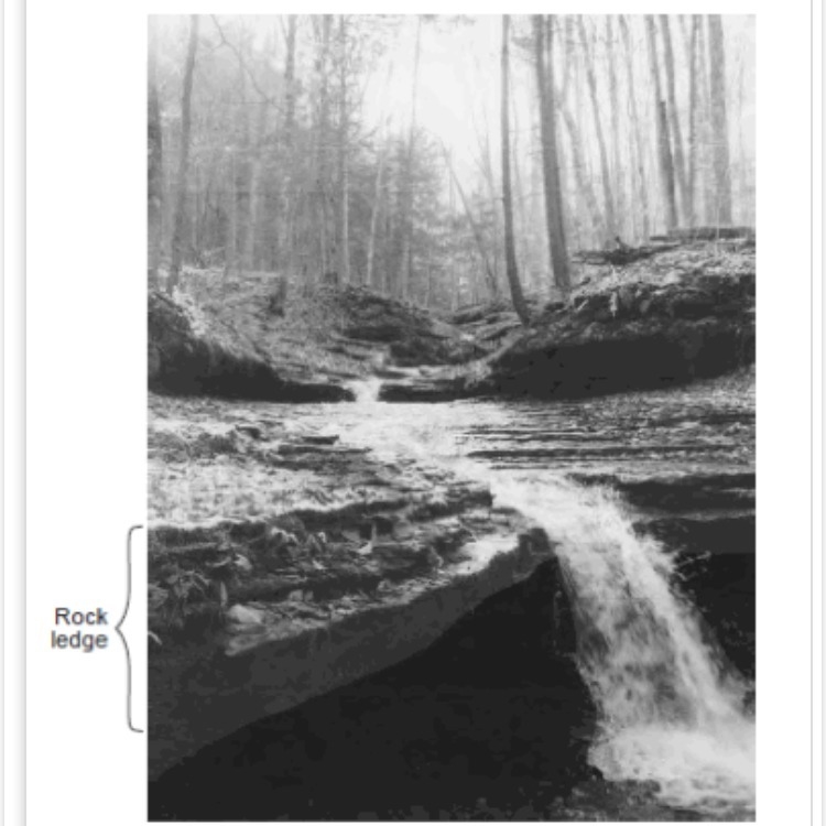 Compared to the bedrock layers above and below the rock ledge shown at the waterfall-example-1