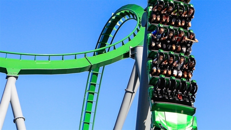 The people on the roller coaster are in motion relative to the people waiting in line-example-1