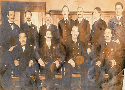 Look at the photograph of Immigrant Inspectors at Ellis Island. Two rows of Ellis-example-1