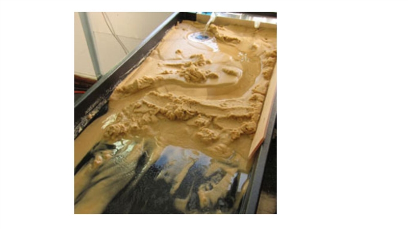 This is an image of a stream table modeling how water can change surface features-example-1