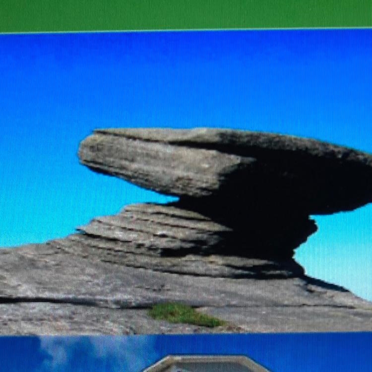 In the photo of the wind sculpture; why are there bigger rocks balancing on smaller-example-1