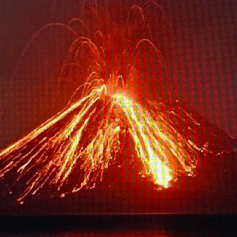 A volcano erupts spewing ash into the air and sending lava flowing down the side of-example-1