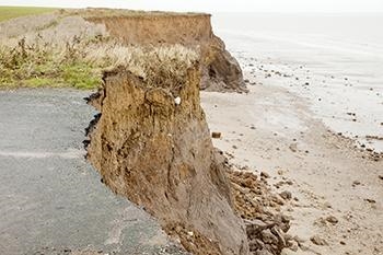 A cliff near the water has been worn away. How did erosion change the shape of the-example-1