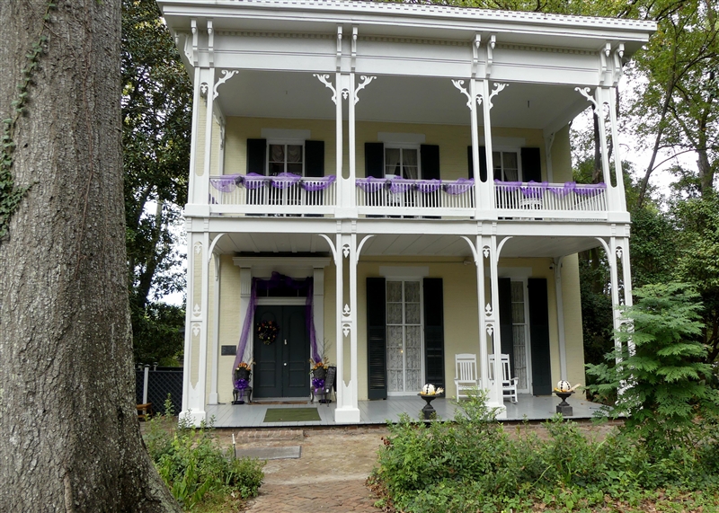 Review the image. The front view of a house with a front porch and balcony. 4 columns-example-1